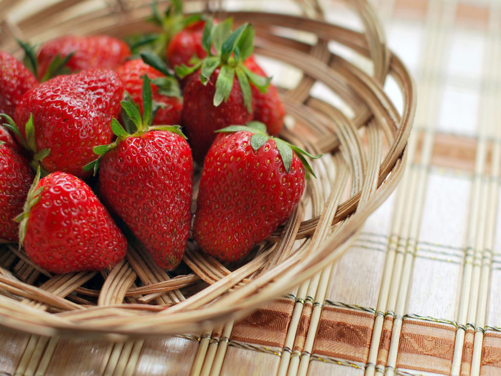 Close-up image of whole strawberries in a wicker basket.