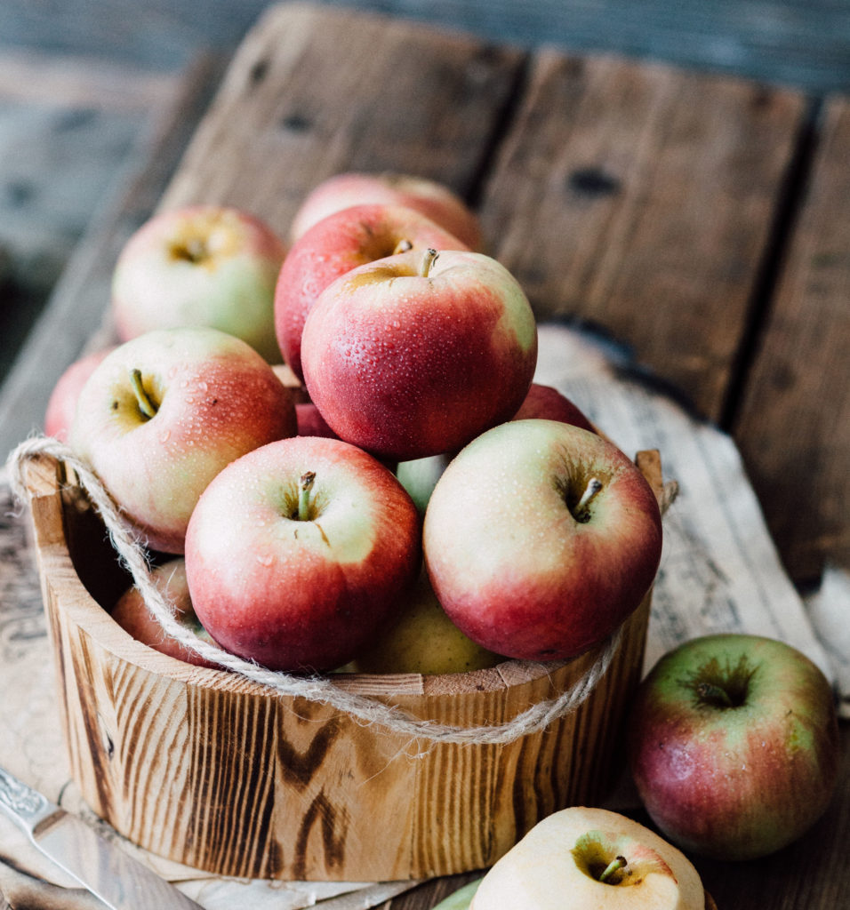 A bunch of apples in a wooden bucket.